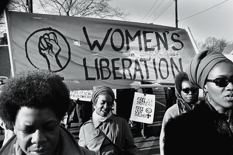 Женщины маршируют за баннером Women's Liberation